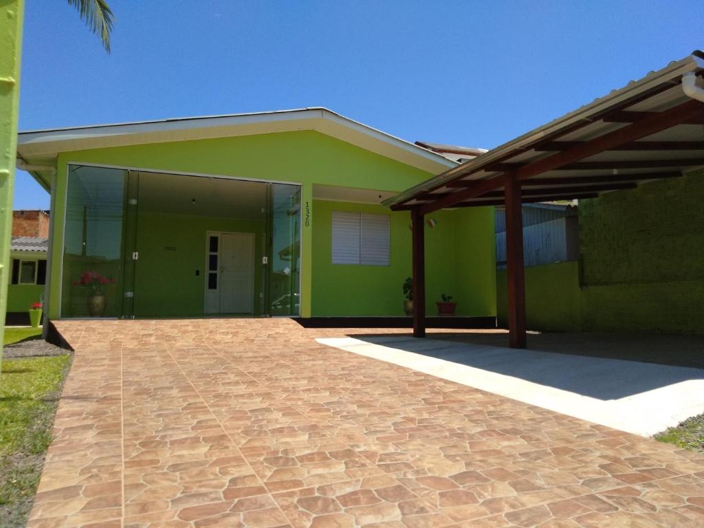 una casa verde con una entrada de ladrillo delante de ella en Casa para aluguel de veraneio em Torres, en Torres