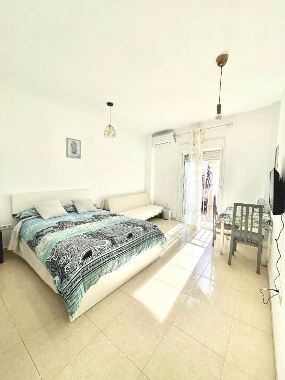 a white bedroom with a bed and a chair at Luna Ensuites Centro in Málaga