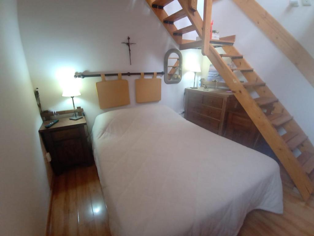 a bedroom with a white bed and a wooden staircase at Resiliencia in Río Gallegos