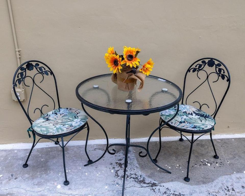 a glass table with two chairs and a vase with sunflowers at 2 Bedroom Suite in Miami in North Miami Beach
