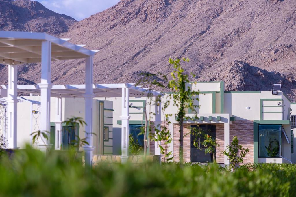 a building with a mountain in the background at AL shoroq Green Resort in Ghubrat Ţanūf