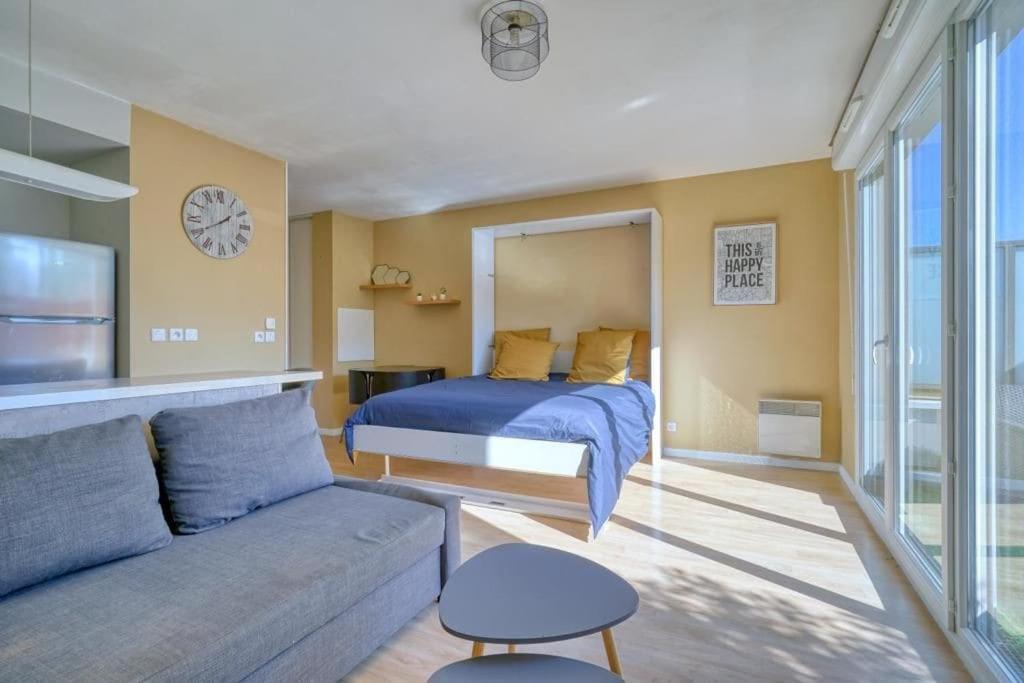 um quarto com uma cama, um sofá e um relógio em Charmant studio avec terrasse et parking em Corbeil-Essonnes