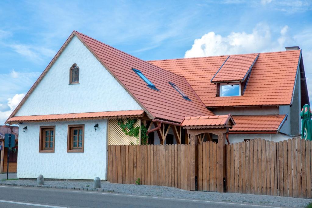 a house with an orange roof and a wooden fence at Pepi Vendégház - Casa de oaspeți Pepi in Joseni