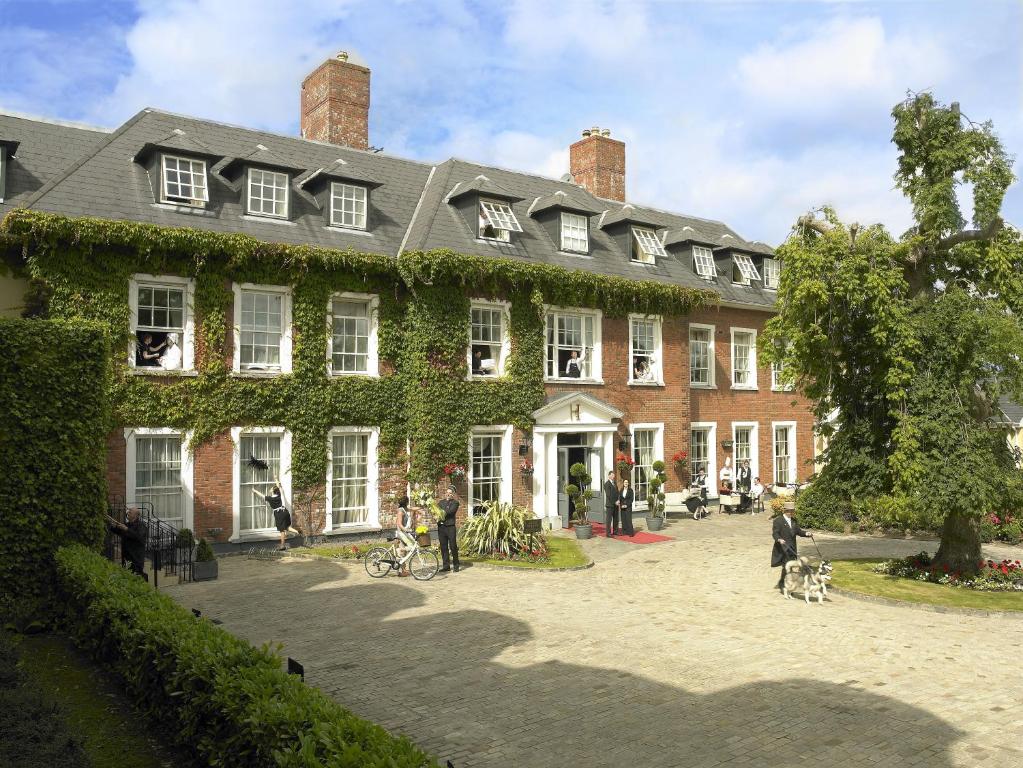 ein großes Backsteingebäude mit Efeu, der darauf wächst in der Unterkunft Hayfield Manor in Cork