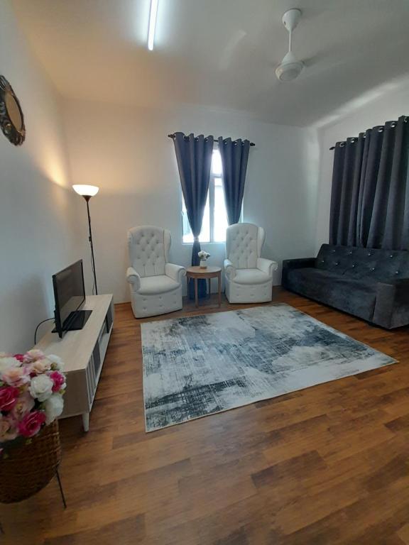 a living room with two chairs and a couch at CASARIA HOMESTAY PD 3Bedrooms Bungalow House in Port Dickson