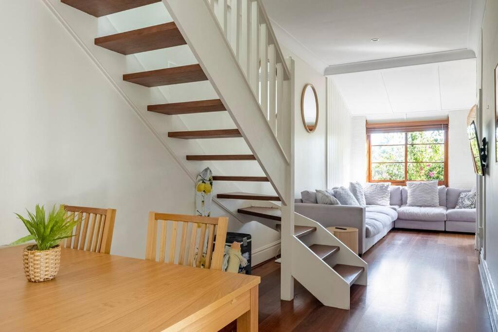 a staircase in a living room with a couch and a table at Steps from Manly Beach in Sydney