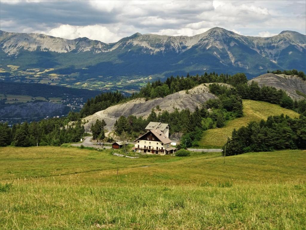 a house on a hill with mountains in the background at Gite montagnard du Fanget in Auzet