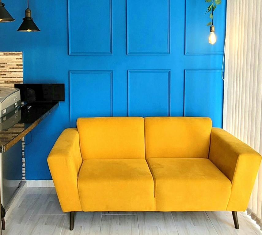 un sofá amarillo en una habitación con una pared azul en Casa Azul, en Medellín