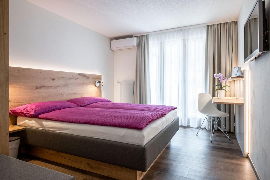 Hotel Zur Traube في Brigerbad: غرفة نوم بسرير كبير مع بطانية ارجوانية