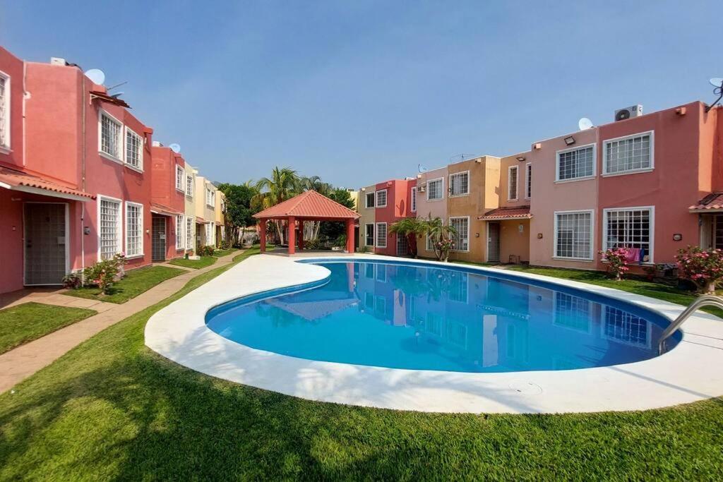 a swimming pool in the middle of a yard with houses at Casa Acá Diamante Gaviotas in Acapulco