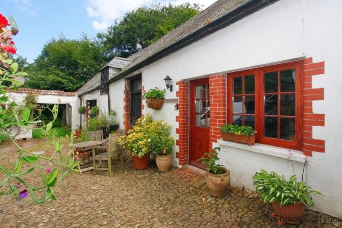 a white house with potted plants in front of it at MONKLEIGH COACHMANS COTTAGE 1 Bedroom in Bideford
