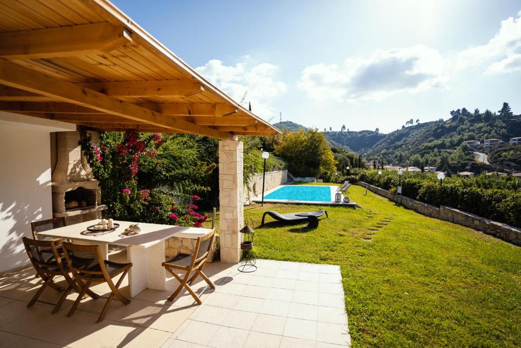 eine Terrasse mit Tisch und Stühlen und einem Pool in der Unterkunft Villa Destiny in Pefkohori