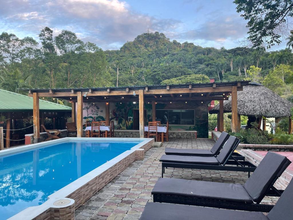 una piscina con 2 tumbonas junto a una casa en Hacienda La Huerta Puerto Plata, 1 BDR en San Felipe de Puerto Plata