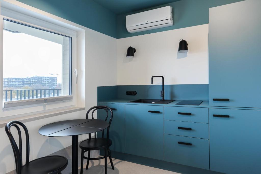 kuchnia ze stołem, umywalką i oknem w obiekcie Odra Apartments we Wrocławiu