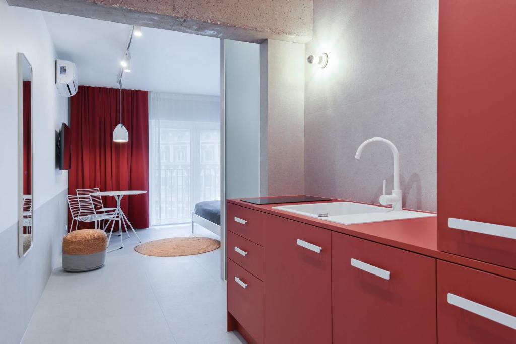 kuchnia z czerwonym blatem i zlewem w obiekcie Odra Apartments we Wrocławiu