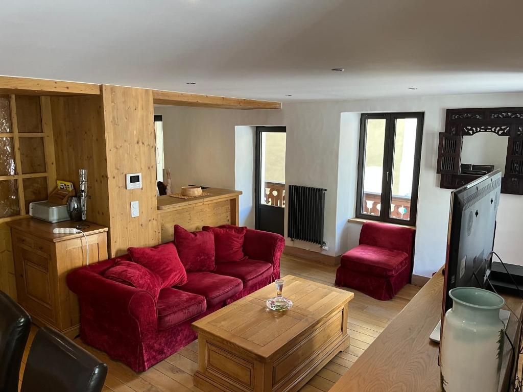 Appartement centre du village brides les bains في بريد-لي-بان: غرفة معيشة مع أريكة حمراء وطاولة