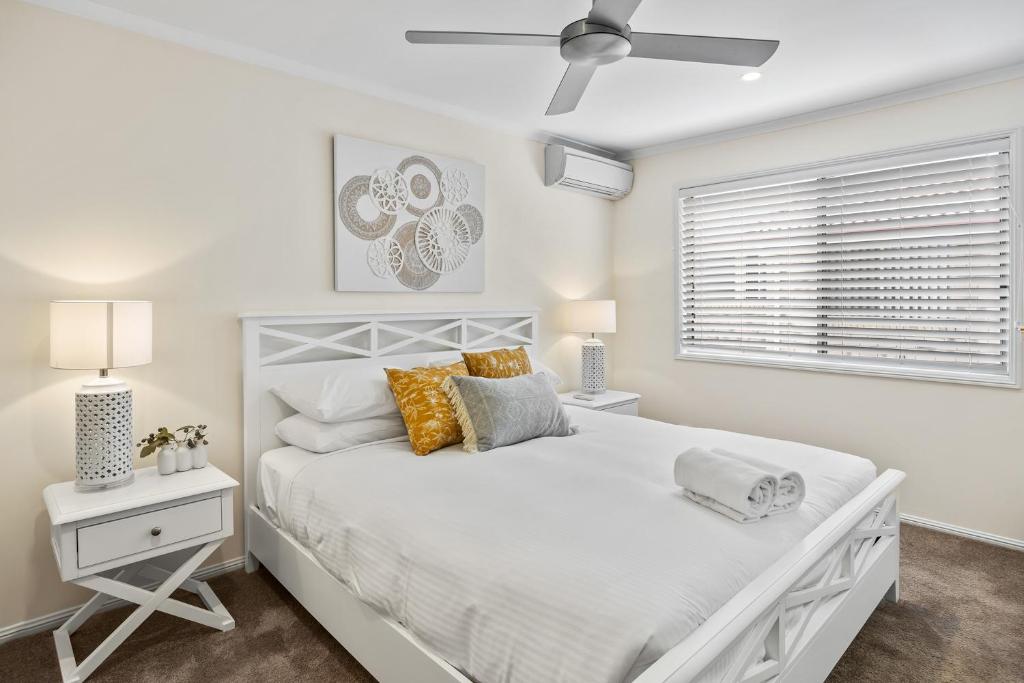 a white bedroom with a large bed and a window at Regency 3 Bedroom Central Town House in Mooloolaba