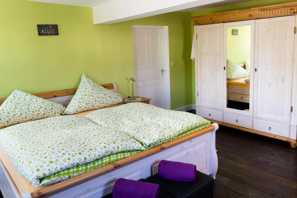 NohenにあるAllerHand Gästezimmer Nohenの緑の壁のベッドルーム1室、紫のクッション付きのベッド1台が備わります。