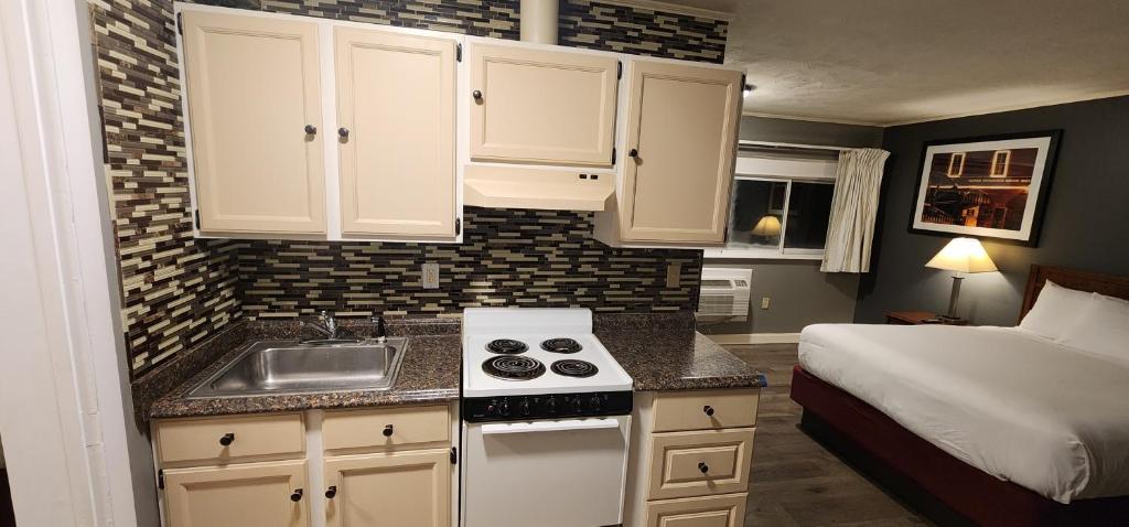 a small kitchen with a sink and a bed in a room at Nashoba Valley Inn & Suites in Ayer