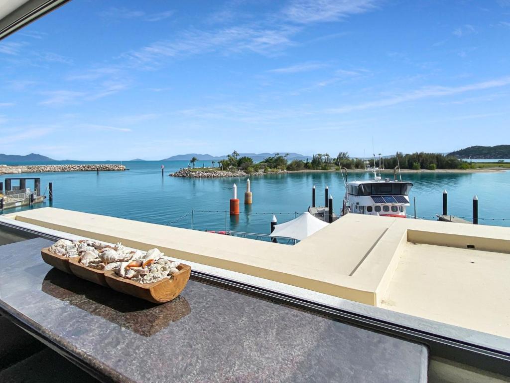 a boat docked at a dock with a bowl of shells at Blue on Blue Superior Studio Room 1271 in Nelly Bay