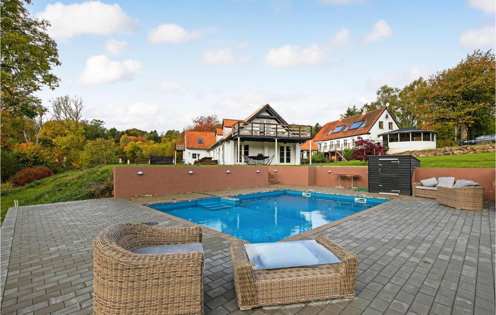 a swimming pool with wicker chairs and a house at 6 Bedroom Cozy Home In Gudhjem in Gudhjem
