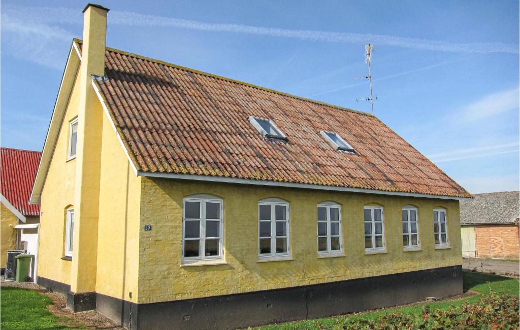 una casa amarilla con techo rojo en Stunning Home In Gudhjem With Kitchen, en Gudhjem