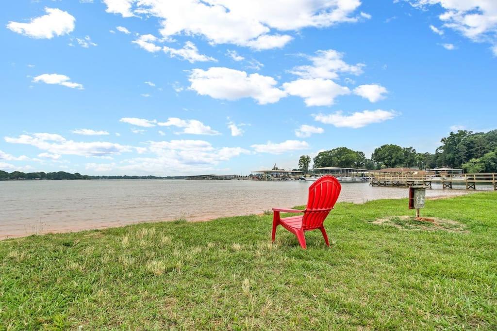 a red chair sitting on the grass near the water at Cozy Lake Home - Jacuzzi King Bed Marina Access in Mooresville