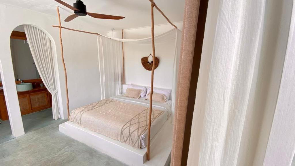 a bedroom with a canopy bed with a ceiling fan at Guru Canggu in Canggu