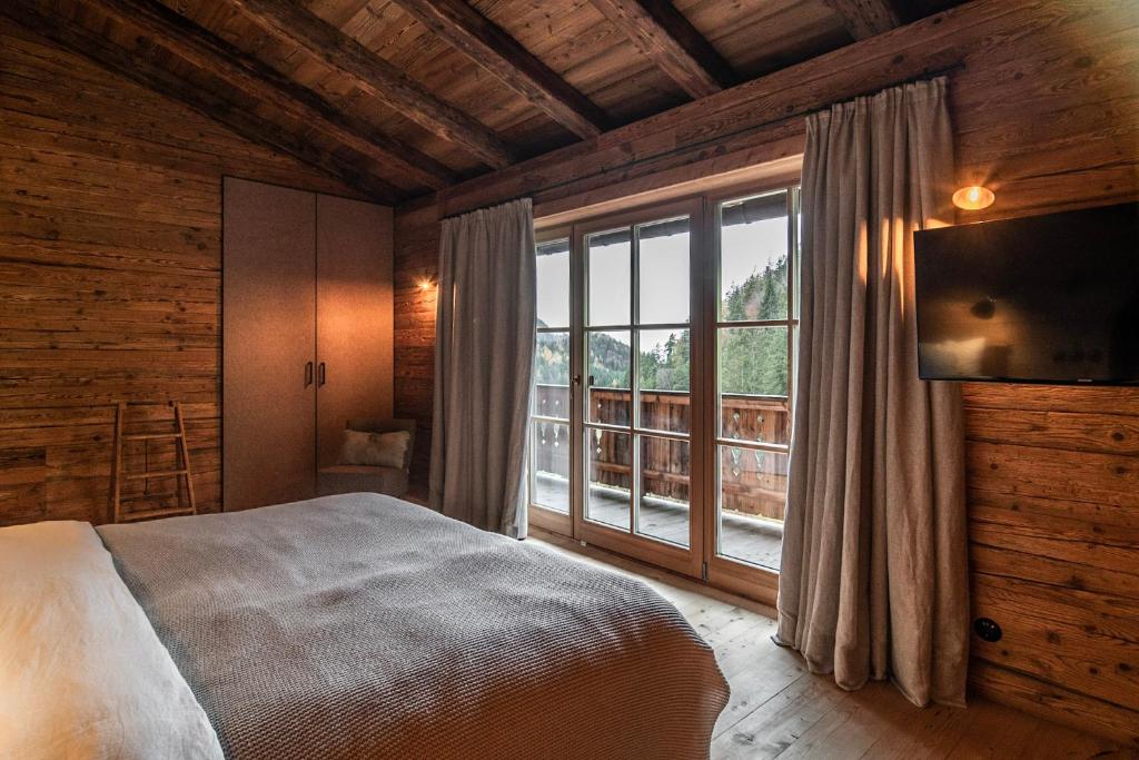 a bedroom with a bed and a large window at Luxury old wood mountain chalet in a sunny secluded location with gym, sauna & whirlpool in Scheffau am Wilden Kaiser