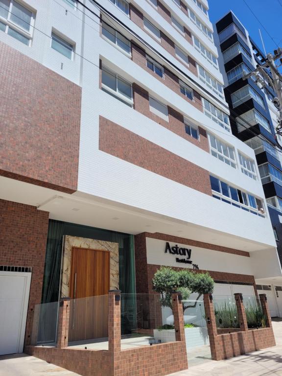 um edifício de apartamentos com uma placa de aania em frente em Lindo apartamento 1 quarto em Capão da Canoa
