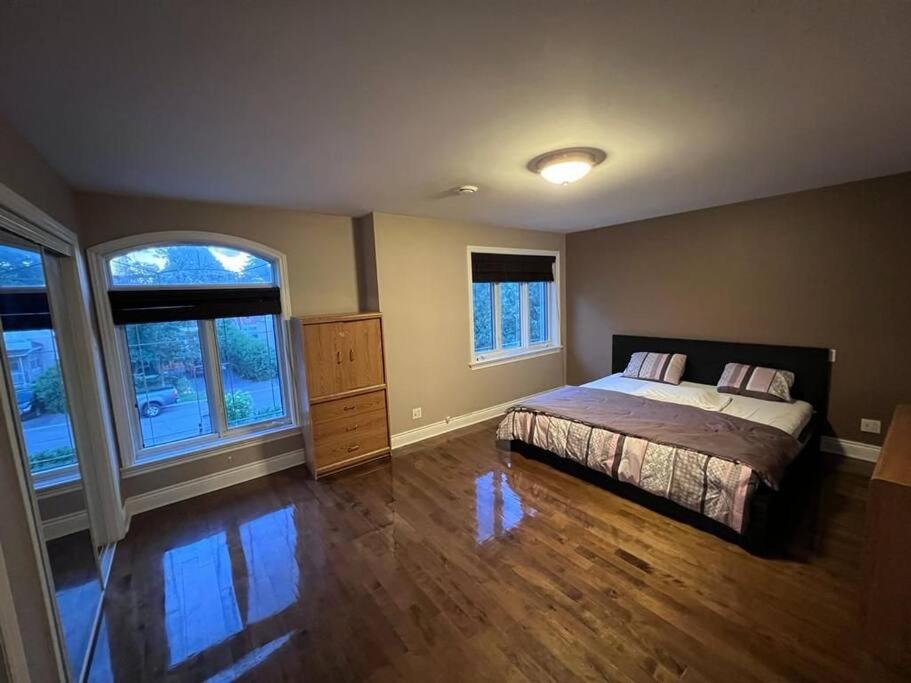 a bedroom with a bed and two windows at Villa Delrose Waterfront in Montréal