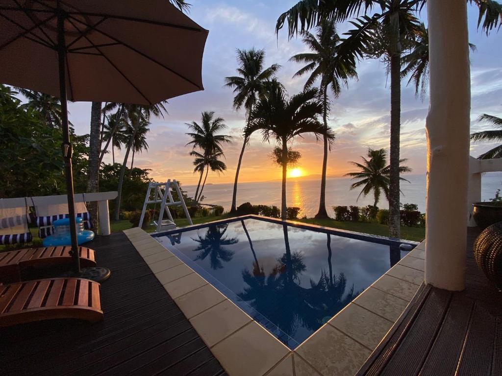 a swimming pool with an umbrella and palm trees at Lomani in Matei