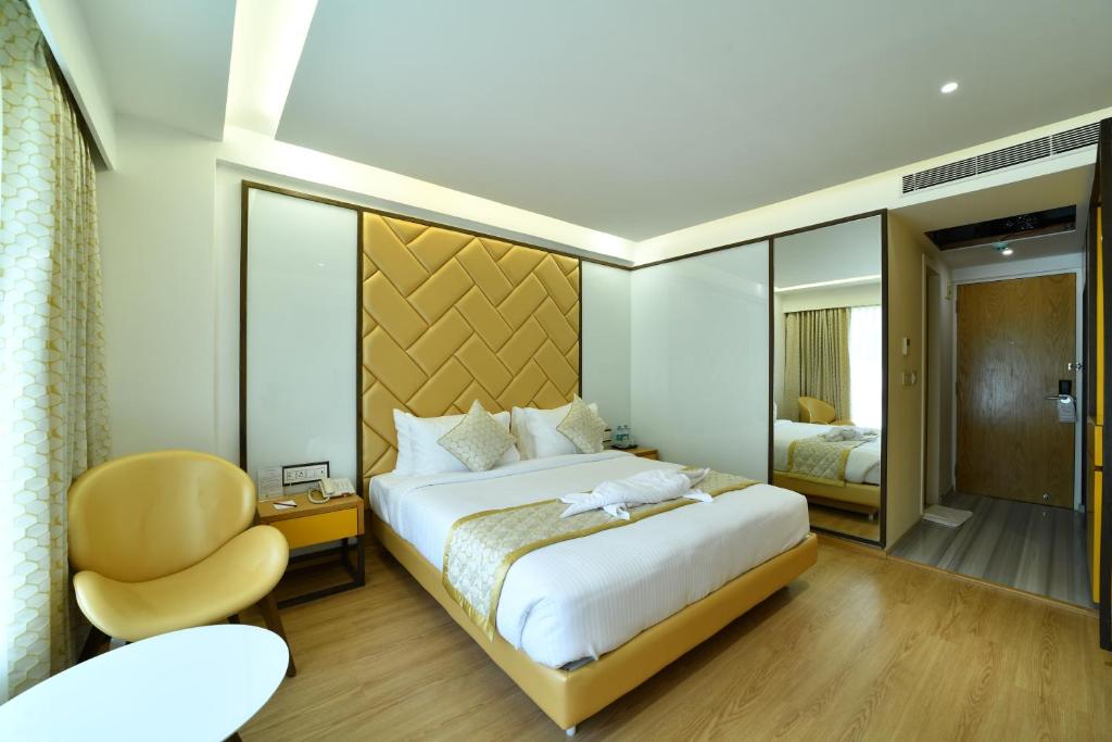 a bedroom with a large bed and a chair at The President Hotel, kumarapark in Bangalore