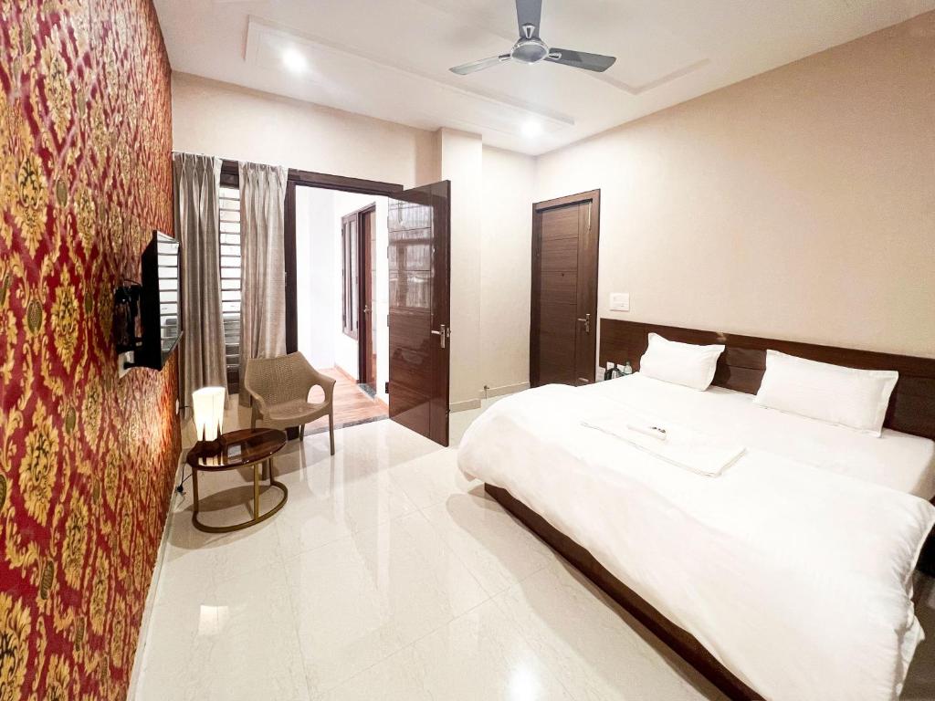 1 dormitorio con 1 cama blanca grande y 1 silla en Radha Krishna Bhawan, Homestay en Vrindāvan