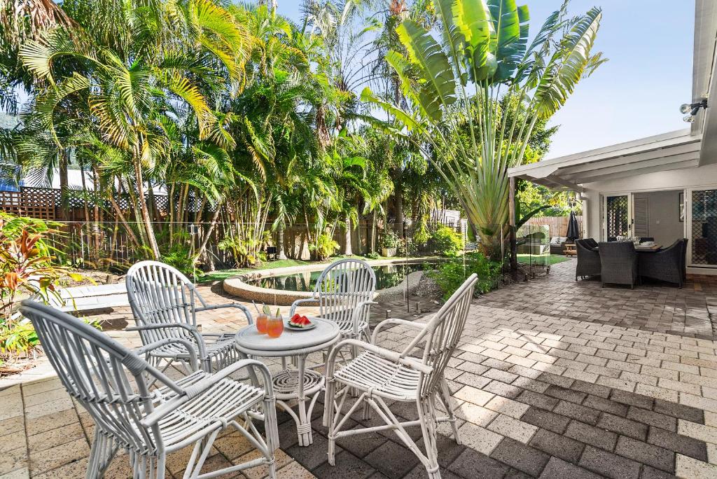 a patio with a table and chairs and palm trees at Sandpipers Beach House in Palm Cove