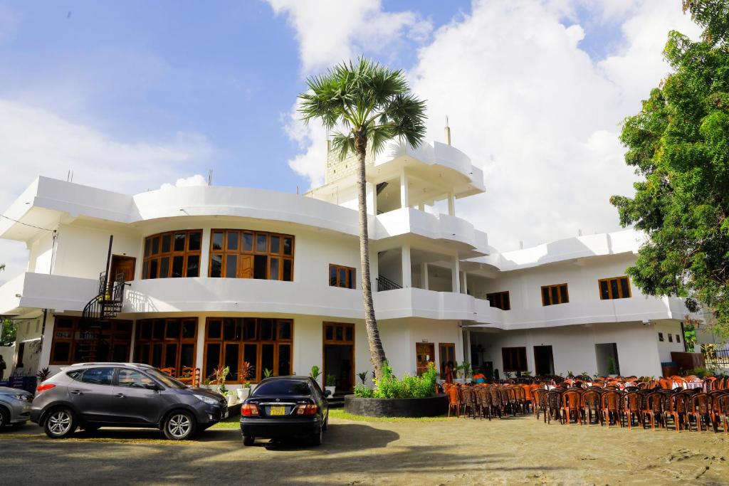 un edificio blanco con una palmera delante en Amis Hotel & Restaurant en Jaffna