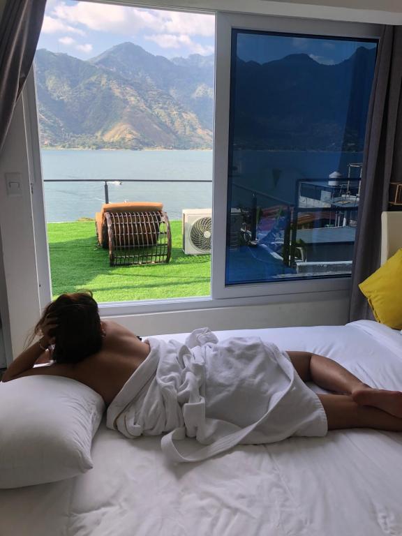 a woman laying on a bed in front of a window at luxury atitlan suites in San Pedro La Laguna