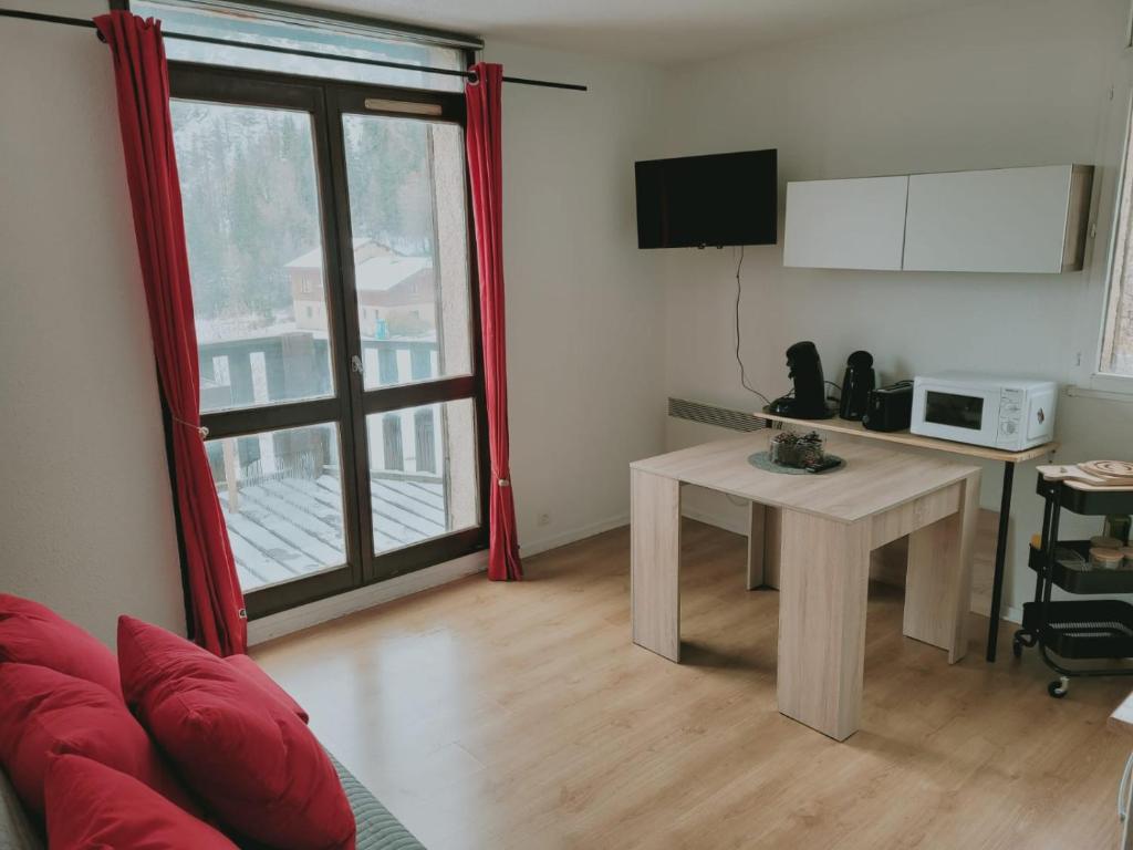 uma sala de estar com uma mesa e um micro-ondas em Jolies Appartement 6 couchages a praloup 1600 avec balcons em Uvernet