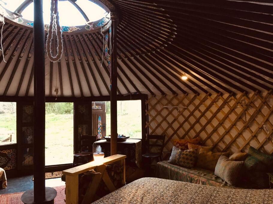 um quarto com uma cama e um sofá numa tenda em Mongolian yurt sleeping 2+2 with outdoor space em Llanbrynmair