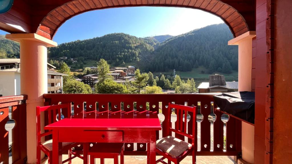 拉富的住宿－la foux d'allos au pied des pistes，阳台上配有红色的桌椅,享有风景。