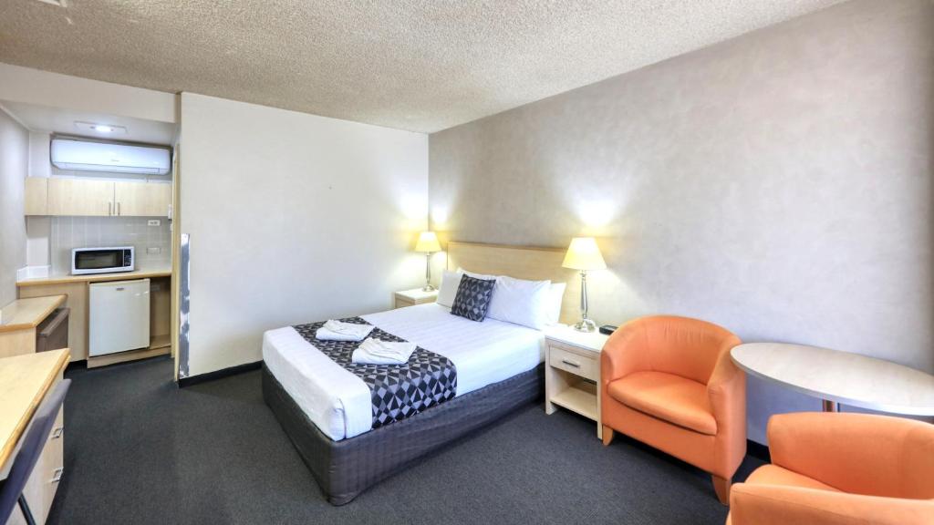 a small hotel room with a bed and a chair at Goulburn Central Motel in Goulburn