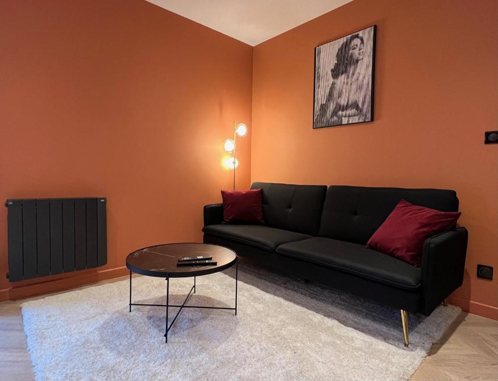 un soggiorno con divano nero e tavolo di Léa Room - Gîte Romantique - Jacuzzi a Bourguébus
