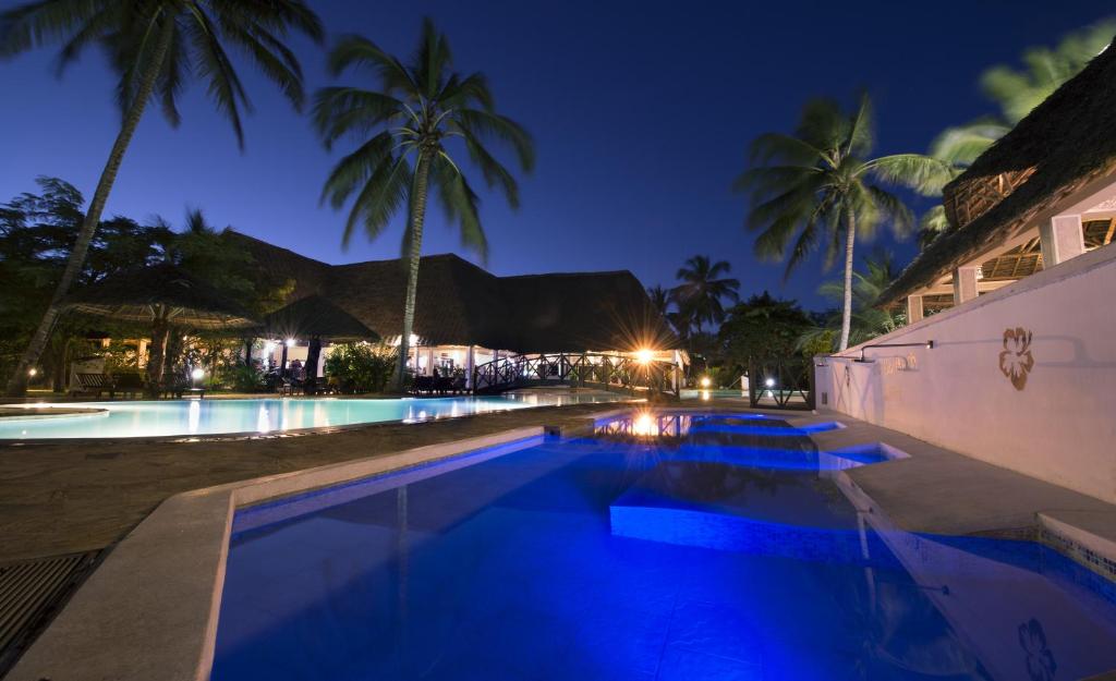 a swimming pool at night with palm trees at Uroa Bay Beach Resort in Uroa