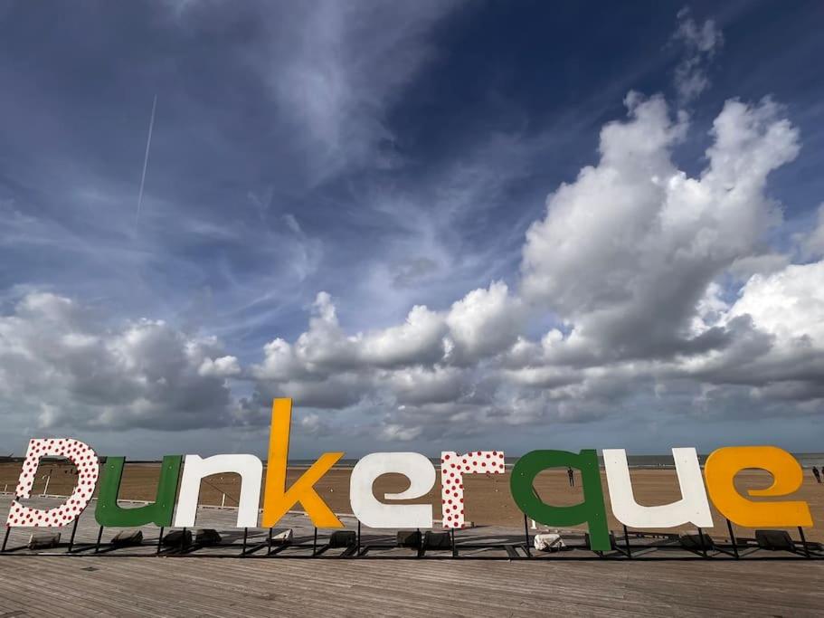 um sinal para uma loja com um céu nublado ao fundo em Dam&HelMalo - 150m de la plus belle plage du Nord. em Dunkerque