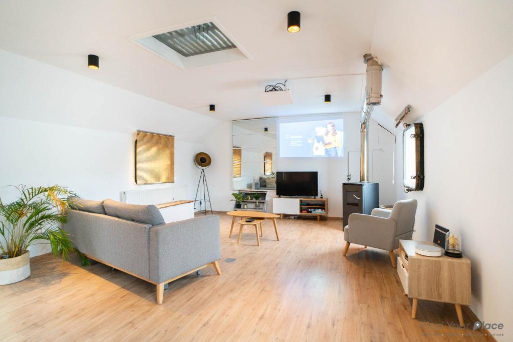 a living room with a couch and chairs and a screen at Arcadia - Péniche de Standing à Namur avec vue sur la Citadelle in Namur