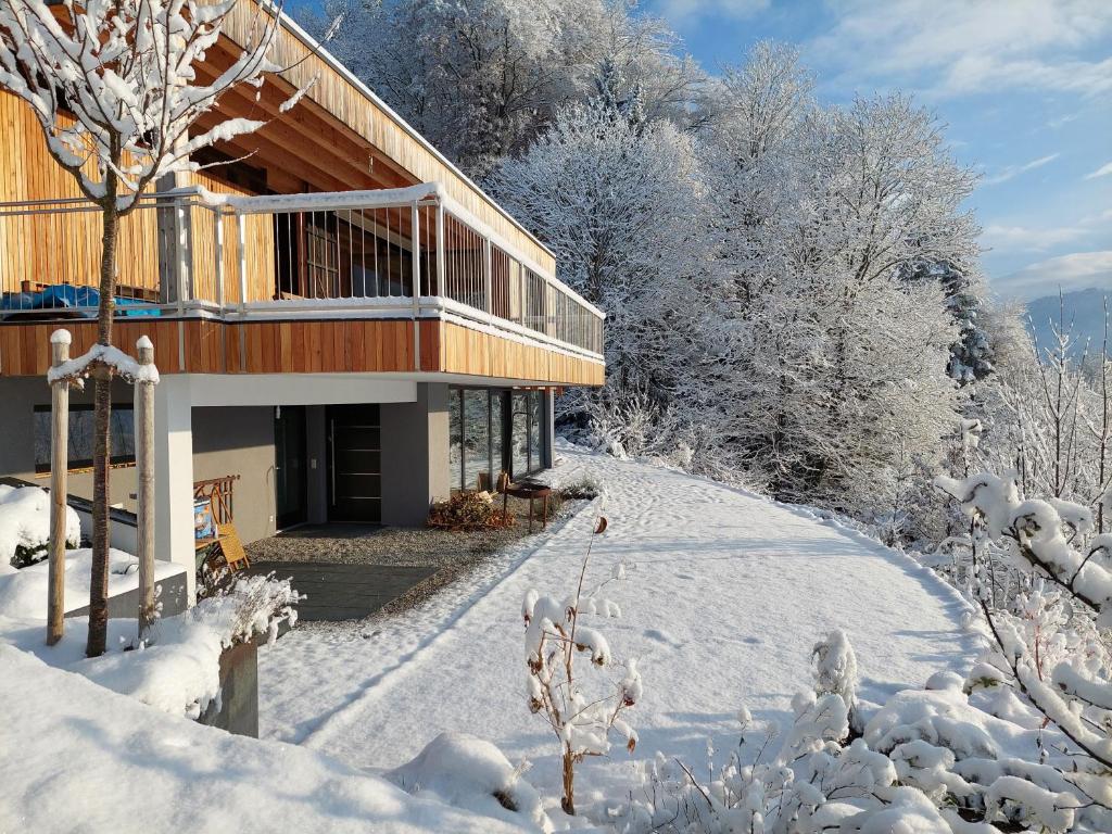 uma casa na neve com árvores cobertas de neve em Casa Farnach em Bildstein