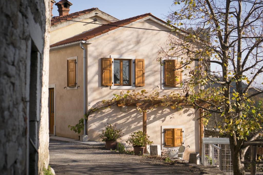 una casa bianca con finestre in legno e vialetto di Apartmaji in sobe Marija Jera Štanjel a Štanjel (San Daniele del Carso)