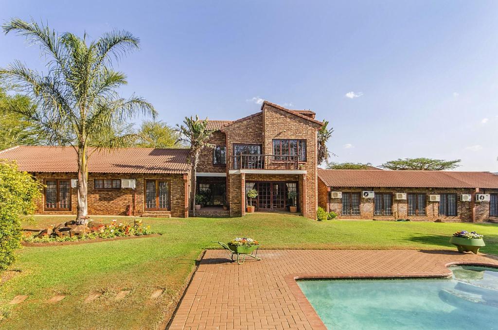 una gran casa de ladrillo con una piscina frente a ella en Peter's Guesthouse, en Pretoria