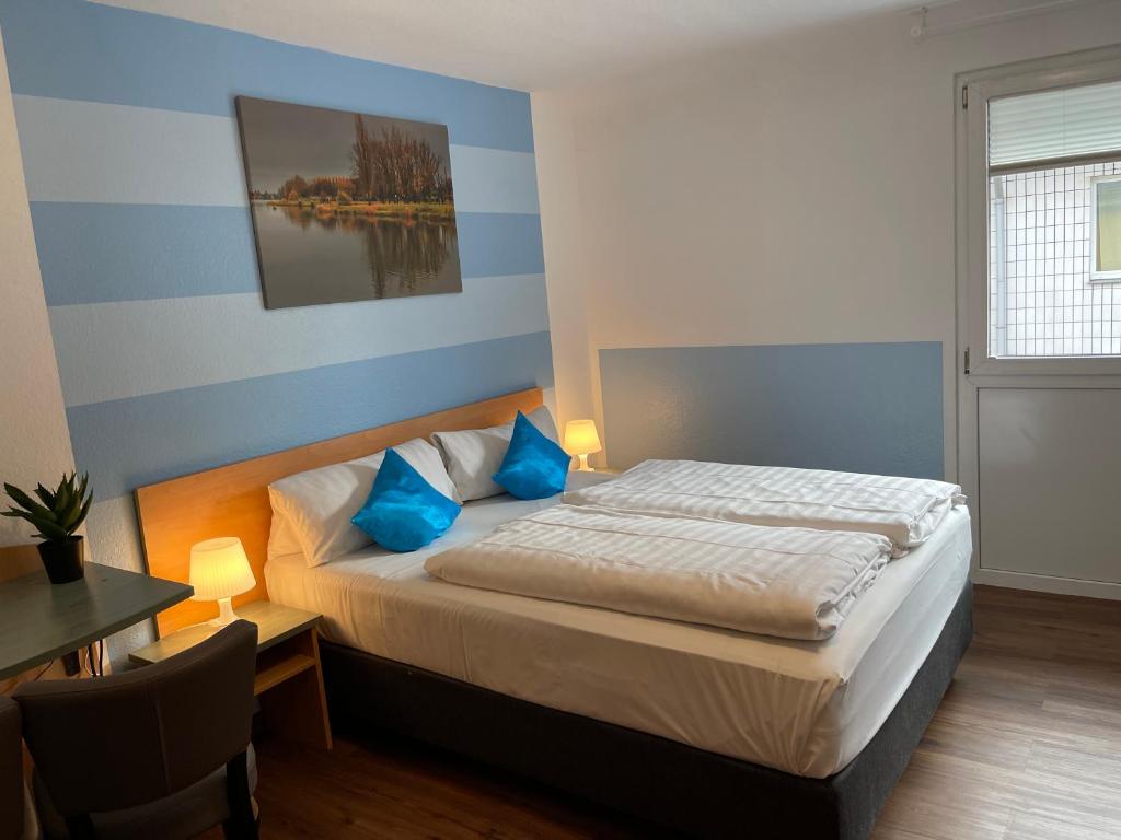 a bedroom with a bed with blue pillows and a table at Residenz Hotel Wuppertal in Wuppertal