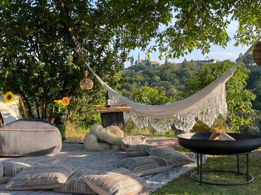 eine Hängematte mit Kissen, einem Tisch und einem Stuhl in der Unterkunft Ferienhaus Leitner in Kitzeck im Sausal